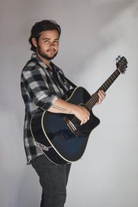 Logan Pietersen performing live on stage with acoustic guitar